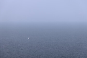 White sailing yacht glides on metal color water of the Tyrrhenian sea, which merges on the horizon...