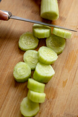 cutting cucumber at home on wooden board close up