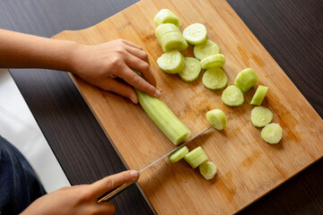 cutting cucumber at home on wooden board close up