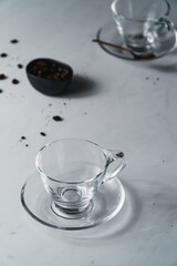 Contemporary style coffee food and drink photo. Set against a white background. Black coffee in glass cup and saucer.
