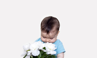 Obraz na płótnie Canvas adorable baby smells hold nose in white peonies bouquet isolated on beige ivory background.free space for text back to school kindergarten concept.space above toddler head.bouquet in outstretched hand