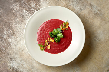 Cream soup of beet with smoked garlic in a bowl. Close-up. Selective focus. Noise added in post-production