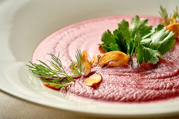 Cream soup of beet with smoked garlic in a bowl. Close-up. Selective focus. Noise added in...
