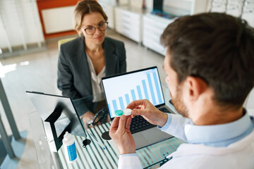 Male optometrist giving pair of contact lens in case to patient offering choice