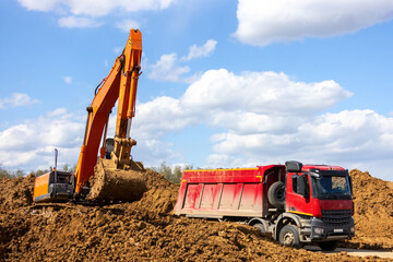 Excavator loading dump truck on the road construction site	
