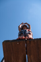 young teen boy ready for a jump in the river on a summer sunny day on vacation superhero shot with selective focus on water drops.