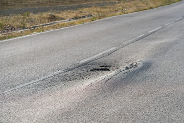 Broken road with holes and cracks built in countryside on hot sunny day. Deformed and expanded...