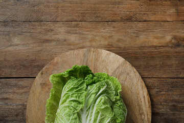 Cutting board with fresh ripe Chinese cabbage on wooden table, top view. Space for text