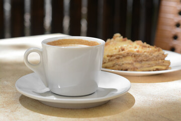Cup of coffee and delicious cake on beige table, closeup