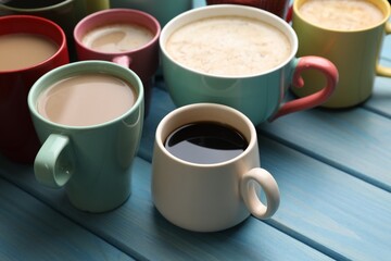 Many cups of different coffee drinks on light blue wooden table