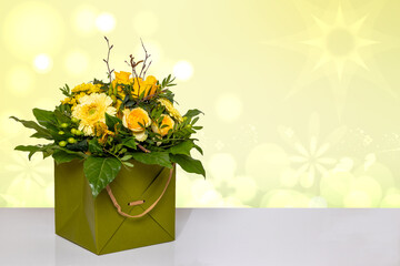 Closeup of a beautiful bouquet of yellow flowers in a decorative green gift box on a bright table over a abstract spring background. Macro. Space for design. Card concept.