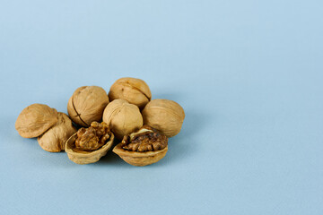 A whole walnut with the shell open on a blue background.