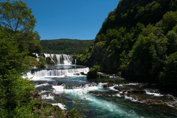 Fototapeta na wymiar a magnificent waterfall called strbacki buk on the beautifully clean and drinking Una river in Bosnia and Herzegovina in the middle of a forest.