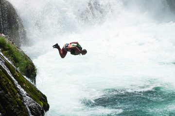 waterfall extreme brave man as superhero running jump and dive from the rock into the wild river...