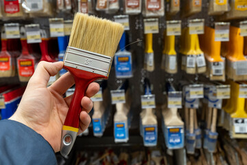 Brush for repair close-up. A man in a hardware store holds a brush for paint and decor. Large...