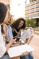 Creative young interracial students with gadgets are discussing project during meeting on street. Guy and girls exchange ideas. Concept lifestyle, education