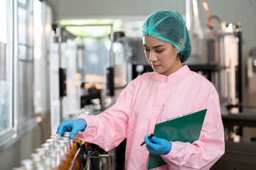 Woman worker checking product bottles on the conveyor belt in the beverage factory. Manufacturer and Inspection quality control