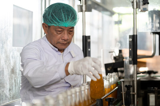 Man worker checking product bottles on the conveyor belt in the beverage factory. Manufacturer and Inspection quality control