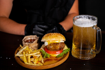 Set of hamburger beer and french fries. A standard set of drinks and food in the pub, beer and snacks. Dark background, fast food. Traditional american food.