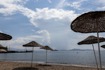 Empty beach, umbrellas and cloudy weather. Turgutreis, Bodrum.