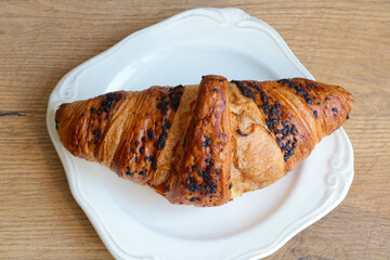 Delicious chocolodic croissant on a white plate in a cafe. Light and delicious breakfast.