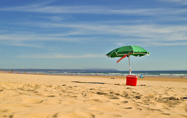 Single umbrella on a perfect beach with clean golden sand and clear turquoise water on a windless and sunny summer day. Tropical background, copy space, top view 