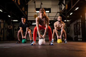 Fit group people in exercise gear standing in a row holding dumbbells during an exercise class at the gym