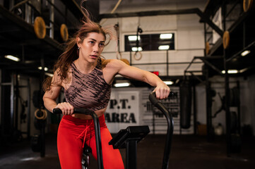 Fototapeta na wymiar Attractive young woman at the gym riding on spinning bike. Healthy Lifestyle and Sport Concepts.