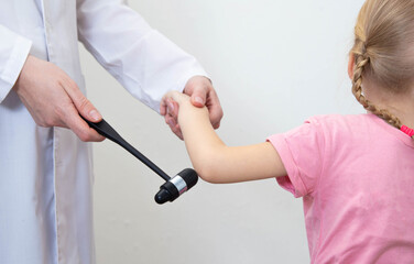 Checking the child's elbow reflex with a neurological hammer, close-up. Nervous system