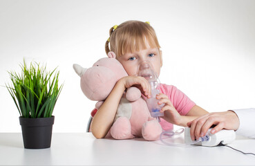 A 5-year-old girl breathes into an inhaler to dilute sputum in case of lung diseases. Treatment of cough in children. Nebulizer therapy