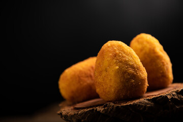 Arancini rice balls. Fried rice balls in paper on brown wooden background. Snack, street food