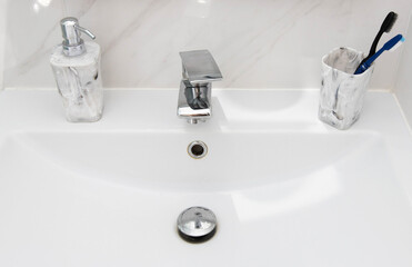 Modern and clean washbasin with pop-up waste. Washbasin interior with liquid soap and toothbrushes.