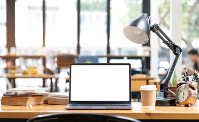 Front view computer laptop with empty screen, coffee cup, pencil holder, notebook and house plant on wooden table.