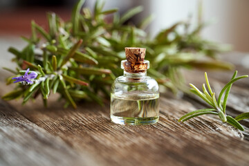 A bottle of aromatherapy essential oil with fresh blooming rosemary
