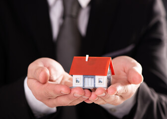 a Businessman hand with model house - home concept