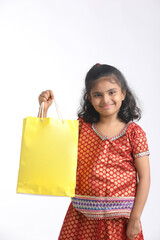 Indian little girl holding shopping bag and giving expression on white background.