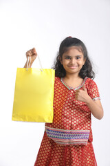 Indian little girl holding shopping bag and giving expression on white background.