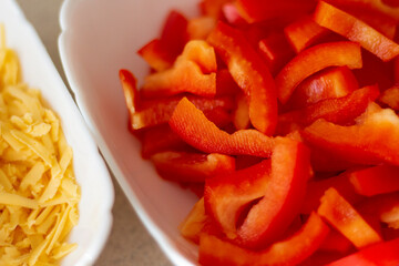 Sliced red bell pepper and cheese in a plate. Natural ingredient for the dish. Preparing lunch and salad. Delicious, healthy, vegetarian and diet food. Closeup photo