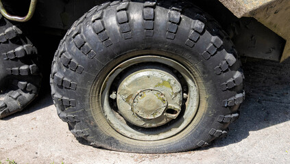 Fototapeta na wymiar A punctured and flat tire of military equipment of the armored personnel carrier. Military conflict, the shelling of the wheel.