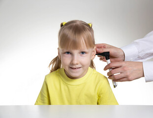 An otolaryngologist examines the ear of a child girl at the age of 5 years. Otoscopy, copy space for text - obrazy, fototapety, plakaty