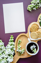 Flatlay Wooden heart shaped plate surrounded by white lilac flowers, cup of coffee and cookies - stylish rustic mockup card invitation