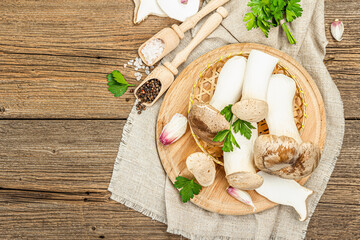 Fresh Pleurotus eryngii mushrooms on wooden background. Raw king oyster eringi with spices and herbs