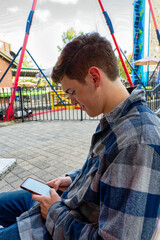 Handsome young man sitting and texting on his cellphone