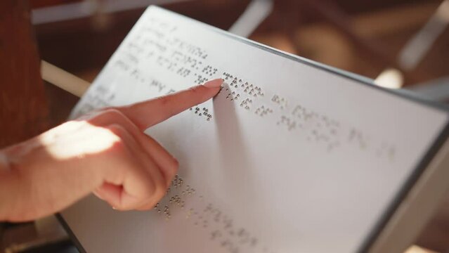 Hands of a Blind reading Braille. Close Up. The hand of a blind man reads the text of a braille book. Braille book