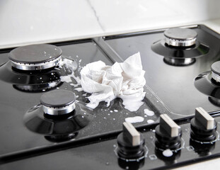 A dirty cloth with a cleaning agent lies on a gas hob. Care and cleaning of grease on a gas stove....