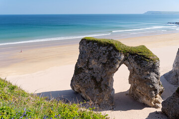 Young woman walks on deserted beach at the White Rocks between Portrush and Bushmills, Northern Ireland. Eroded limestone cliffs