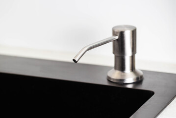 Modern built-in liquid soap dispenser in the kitchen sink. Copy space for text