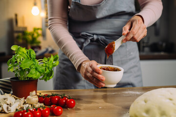 woman prepare tomato dressing for pizza