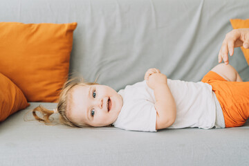 A small child lies on the sofa and smiles.