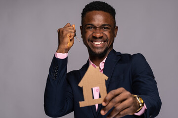 businessman holding cardboard house and key rejoicing